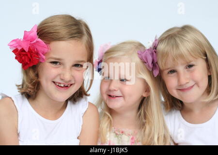 Three blonde sisters portrait lying tummies smiling laughing, sibling love, family love concept, togetherness, connection, best friends, besties hats Stock Photo