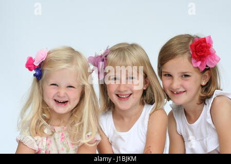 Three blonde sisters portrait lying tummies smiling laughing, sibling love, family love concept, togetherness, connection, best friends, besties hats Stock Photo