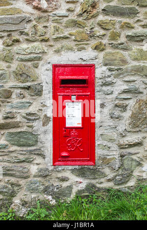 Red post box mounted in a stone wall in Devon Stock Photo