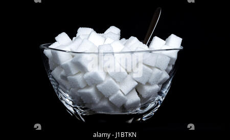 Glass bowl full of sugar cubes - concept of consuming too much sugar Stock Photo