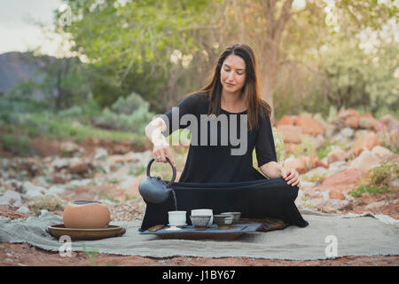 Sarah Hedden prepares tea outdoors on a blanket. Stock Photo