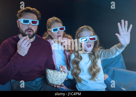 Shocked family in 3d glasses watching movie and eating popcorn Stock Photo