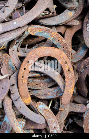 Heap of used and worn rusty Horseshoes outside blacksmith farriers shop or smithy Stock Photo