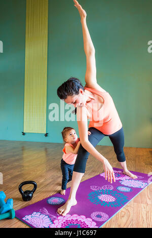 Mixed Race expectant mother practicing yoga and watching daughter Stock Photo