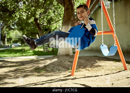 Hispanic boy on swing at park Stock Photo