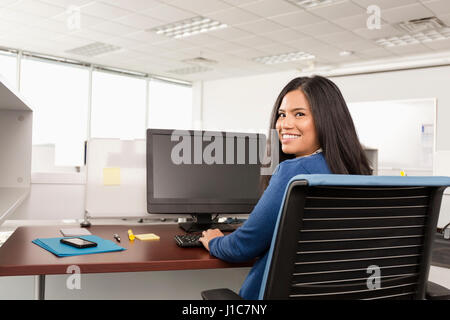 Smiling Pacific Islander woman using computer in office Stock Photo
