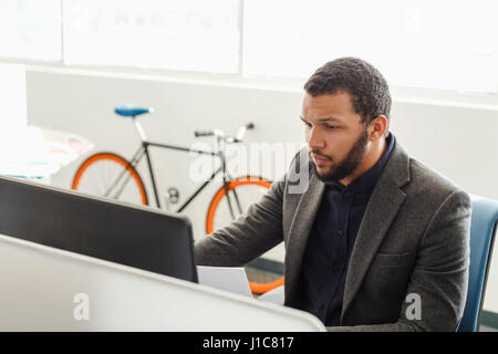 Mixed Race man using computer in office Stock Photo
