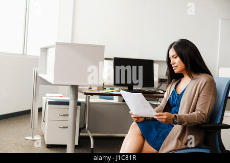 Pacific Islander woman reading paperwork in office Stock Photo
