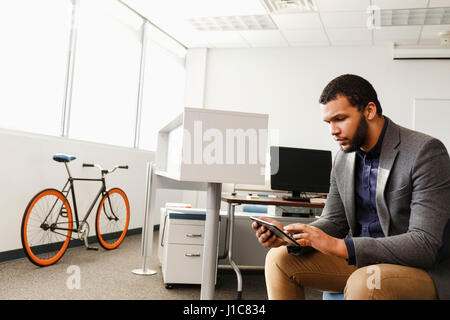 Mixed Race man using digital tablet in office Stock Photo