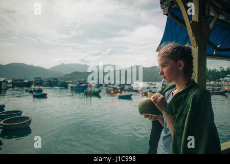 Caucasian woman drinking milk from coconut with straw Stock Photo