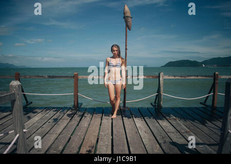 Caucasian woman wearing bikini standing on dock Stock Photo