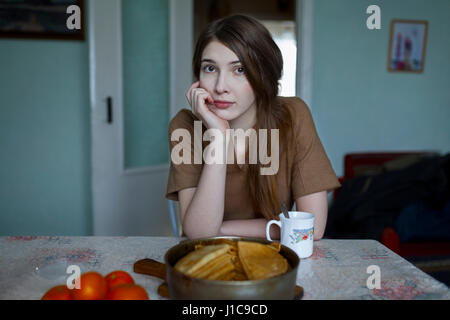Pensive Caucasian woman sitting at table Stock Photo