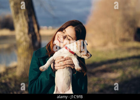 Caucasian woman lifting an hugging dog Stock Photo