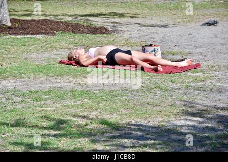 Pregnant woman sun bathing in field Stock Photo