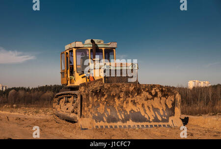 Old yellow bulldozer on the road construction site on sunset Stock Photo