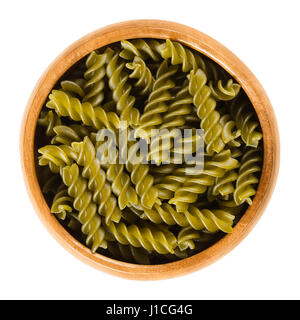 Green peas fusilli pasta in wooden bowl. Uncooked dried glutenfree noodles made from Pisum sativum flour. Short length corkscrew shaped pasta. Stock Photo