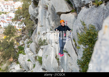 Woman hanging on Tibetan bridge climbing up to the hill. Horizontal outdoors shot Stock Photo
