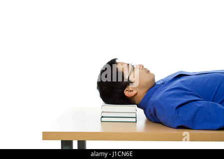 An isolated shot of a businessman sleeping on a table using books as the pillow Stock Photo
