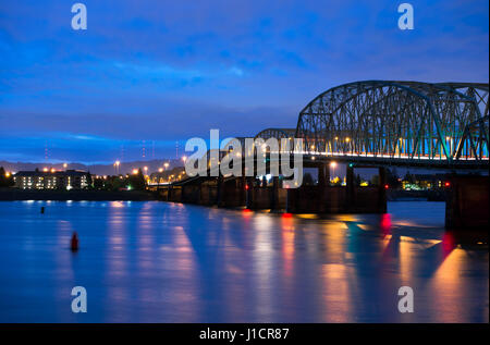 Elegant night lights sectional drawbridge arched sections of metal structures on concrete pillars. Bridge connects the two banks of the Columbia River Stock Photo