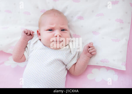 Detail shot of baby's hand on pink sheets with cloud pattern. Stock Photo