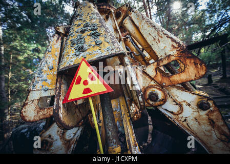 Warning sign in front of irradiated scrap bucket in Pripyat city of Chernobyl Nuclear Power Plant Zone of Alienation around the nuclear reactor disast Stock Photo