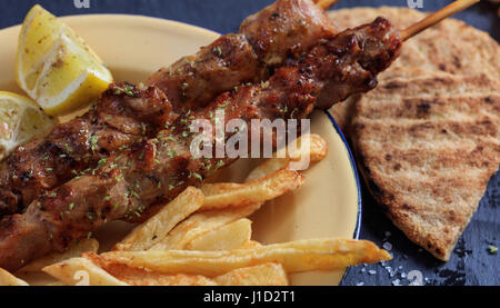 Grilled meat skewers and fried potatoes in a dish