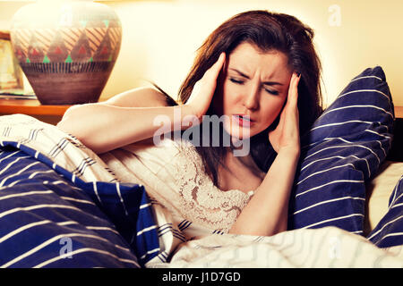 Young sick woman lying on her bed in bedroom. Instagram style Stock Photo
