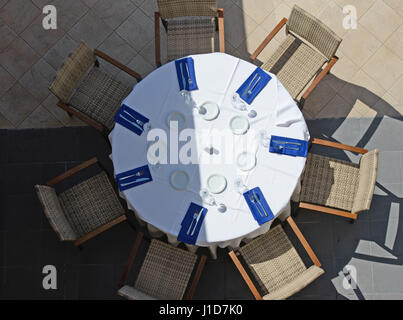 High angle view of table with initial setting and chairs are on tiled floor in bright sunlight. Stock Photo