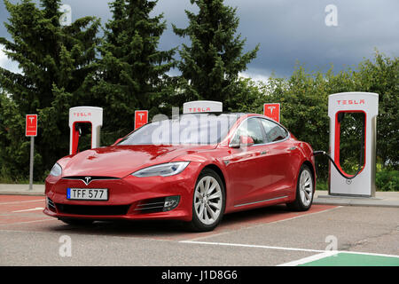 PAIMIO, FINLAND - JULY 31, 2016: Tesla Model S luxury sedan with new design on the vehicle exterior is being charged at Tesla Supercharger Station. Stock Photo