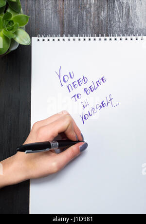 Female hands writing motivational message in a notebook Stock Photo