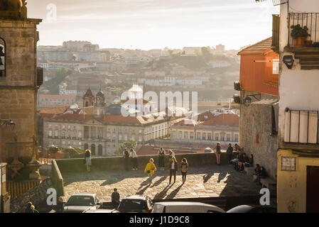 Porto Portugal, tourists view the skyline of Porto at sunset from a terrace below the cathedral, or Se, sited in the centre of the old town district. Stock Photo