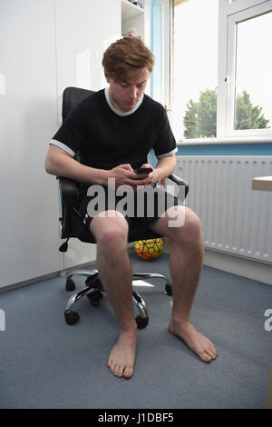 Portrait of a nineteen year old teenage boy examining his text messages Stock Photo