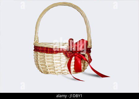 Woven container with round handle b of soft golden color, decorated with a bow of red ribbon Stock Photo
