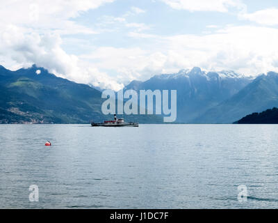 Lake Como - Italy: 2016 June 18: Old boat passengers traveling on the lake. In the background the mountains of Valtellina. Stock Photo