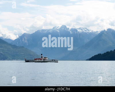 Lake Como - Italy: 2016 June 18: Old boat passengers traveling on the lake. In the background the mountains of Valtellina. Stock Photo