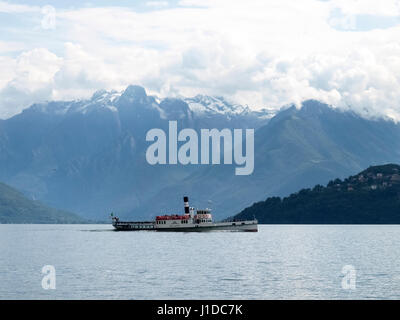 Lake Como - Italy: 2016 June 18: Old boat passengers traveling on the lake. In the background the mountains of Valtellina. Stock Photo
