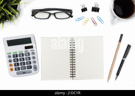 Open spiral blank notebook with calculator, pen, pencil, eye glasses, cup of coffee and small flower plant on white desk table, flat lay top view Stock Photo