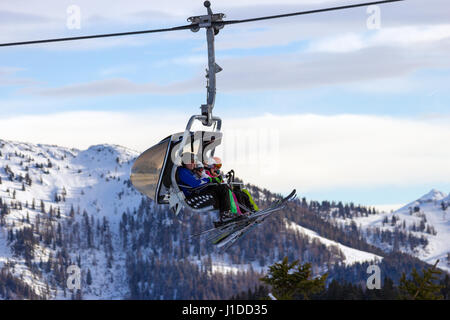 FLACHAU, AUSTRIA - DEC 27, 2012: Skiiers on a ski lift to a piste in the Austrial Alps. These pistes are part of the Ski Armada network, the largest o Stock Photo