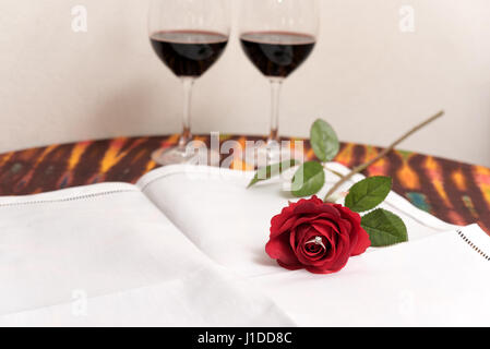 Marriage proposal concept with Diamond ring inside red rose over two wine glasses background with copy space Stock Photo