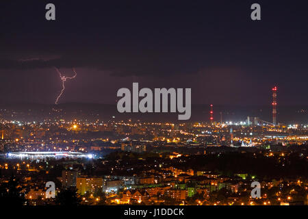 Lightning storm over city skyline at night. Kielce, Poland, Holy Cross Mountains. Stock Photo