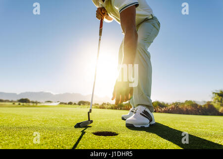 Shot of a golf player taking out the ball from hole. Golfer picking the ball from hole after successful put Stock Photo