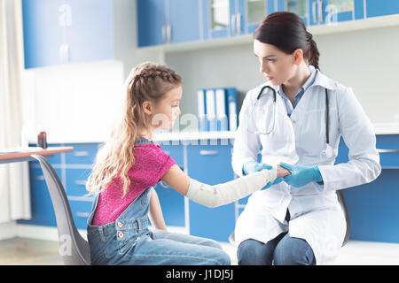 Woman doctor bandaging hand of little girl in hospital Stock Photo