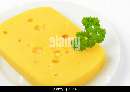 close up of emmental cheese with holes on white plate Stock Photo