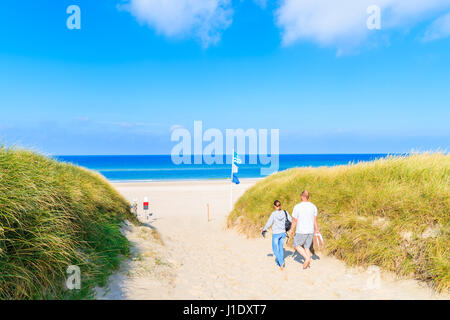 Unidentified couple of people walking to beach among grass sand dunes, Sylt island, Germany Stock Photo