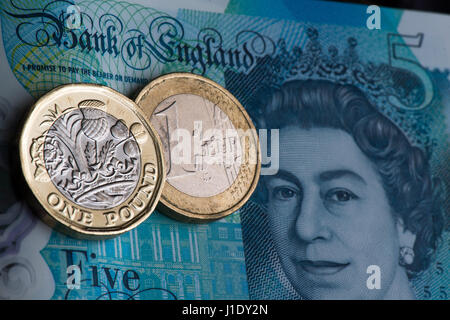 New one pound coin next to a one euro coin on a new Bank of England £5 note. Stock Photo