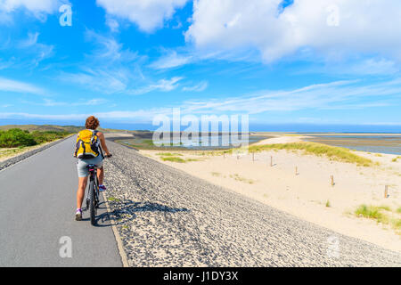 Young woman on bike during trip along coast of Sylt island near List village, Germany. Stock Photo