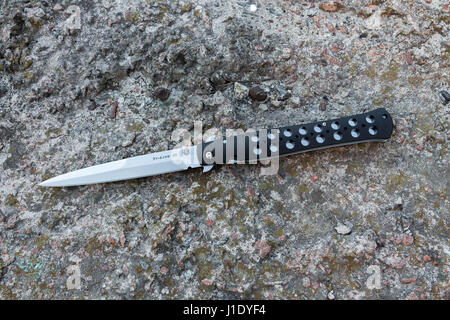 Large knife on stone background. The handle of the knife to the right. Stock Photo