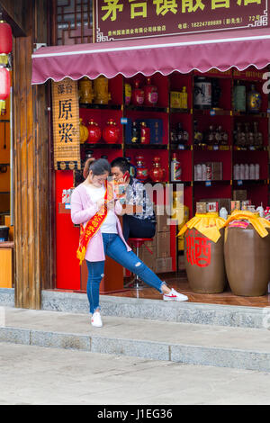 Guizhou Province, China.  Shopkeepers Using their Cell Phones, Souvenir and Gift Shop Area, Yellow Fruit Tree (Huangguoshu) Waterfall Scenic Area. Stock Photo