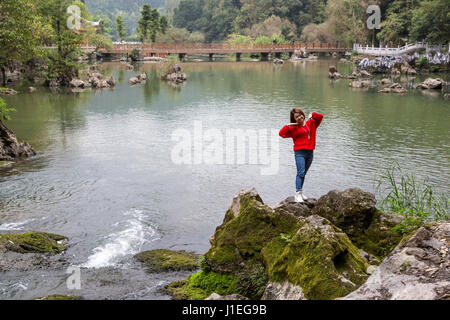 China, Guizhou, Dragon Palace Scenic Area.  Tourist Posing for a Photo by a Friend. Stock Photo