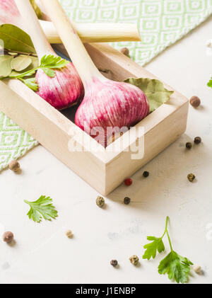 Garlic purple with Parsley in wooden box on a white stone background. A lot of empty space. Stock Photo